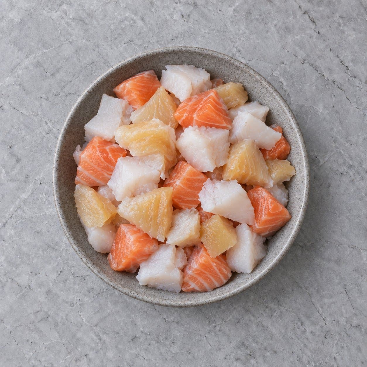 Raw haddock, smoked haddock and salmon in a stoneware bowl