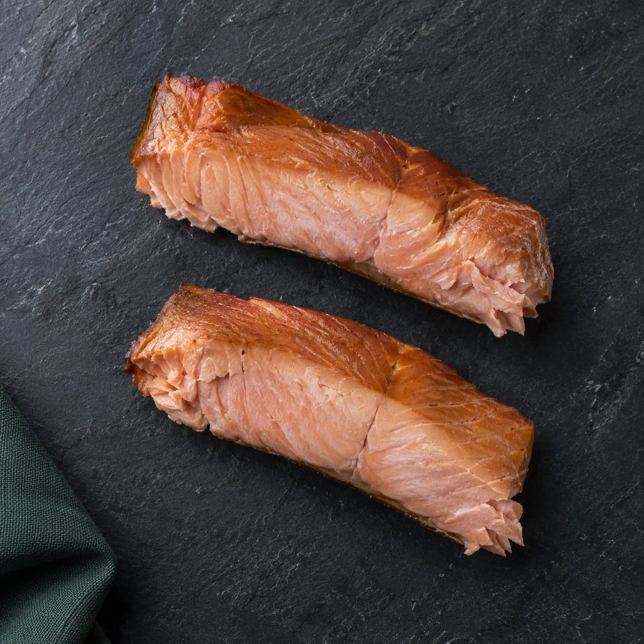 Two portions of hot-smoked salmon on slate